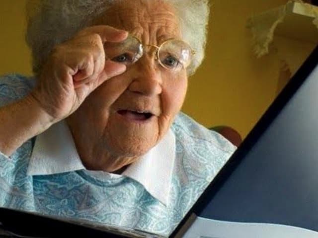 Confused old women looks at her laptop while learning to code